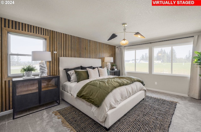 bedroom with a textured ceiling, multiple windows, and carpet floors