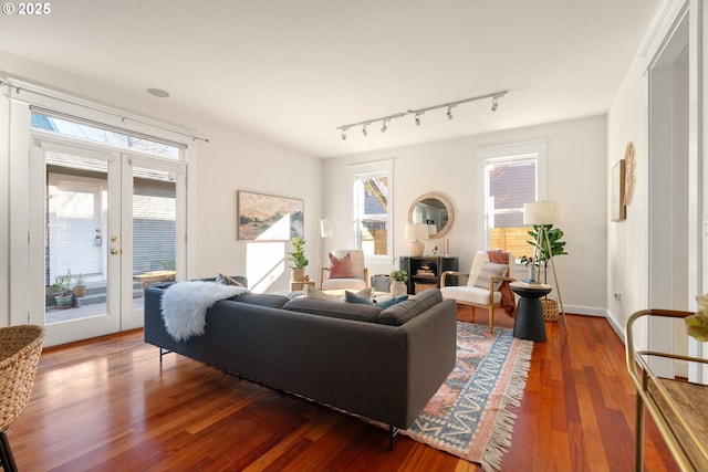 living room featuring plenty of natural light, track lighting, dark hardwood / wood-style floors, and french doors