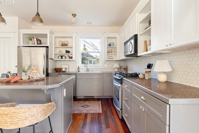 kitchen with sink, a breakfast bar area, appliances with stainless steel finishes, gray cabinetry, and hanging light fixtures