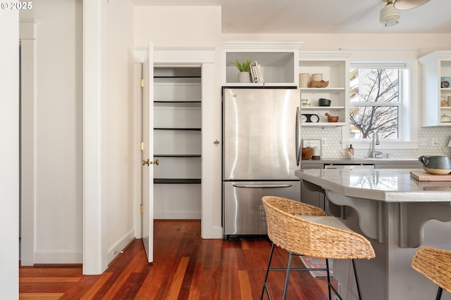 kitchen featuring tasteful backsplash, stainless steel appliances, dark hardwood / wood-style floors, and a breakfast bar