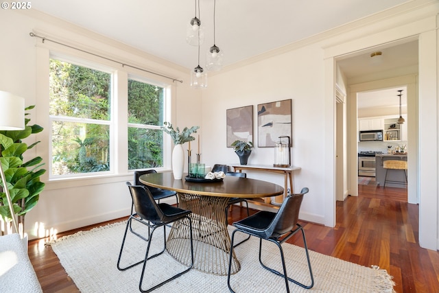 dining area with ornamental molding and dark hardwood / wood-style floors