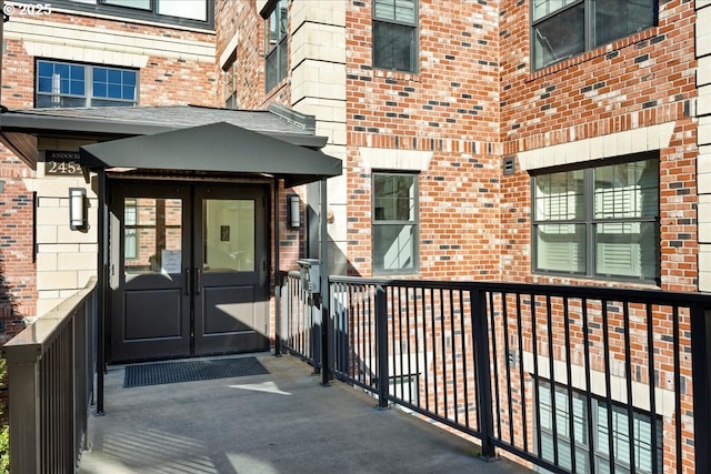 view of exterior entry featuring brick siding and french doors