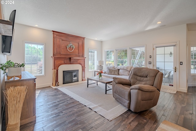 living room with dark wood-style floors, a large fireplace, and a textured ceiling