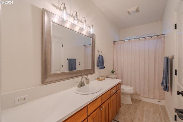 bathroom featuring toilet, a shower with shower curtain, wood finished floors, vanity, and visible vents