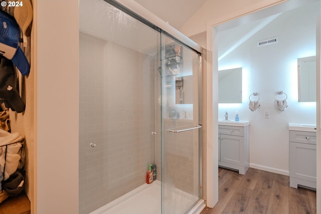 full bath featuring a stall shower, visible vents, lofted ceiling, wood finished floors, and vanity