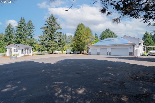 exterior space featuring a garage, an outbuilding, stone siding, and fence