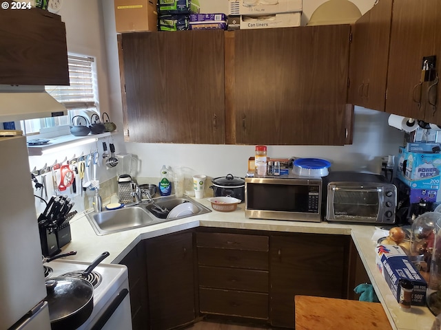 kitchen with light countertops, stainless steel microwave, a sink, and a toaster