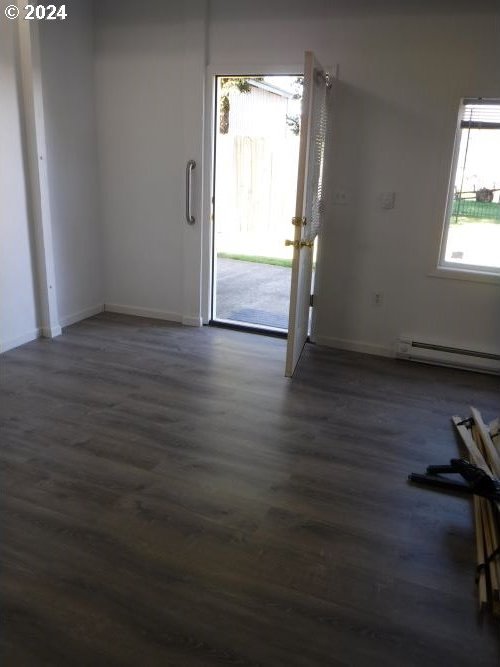 foyer entrance featuring dark wood-style flooring, a baseboard radiator, and baseboards