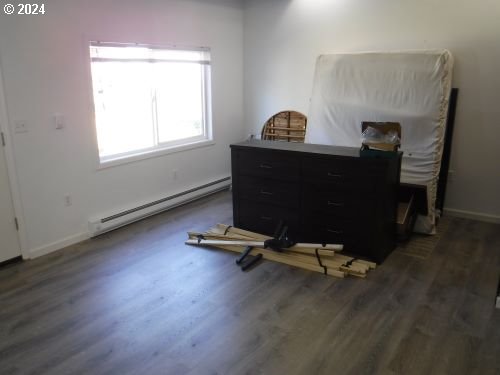 bedroom with a baseboard radiator, baseboards, and wood finished floors