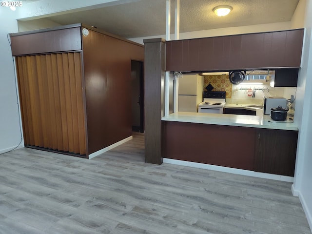 160 Spring St, Gardiner, OR 97441 - kitchen featuring a textured ceiling, wood finished floors, light countertops, a peninsula, and white appliances