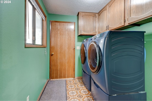 laundry room featuring cabinets, a textured ceiling, and washing machine and clothes dryer