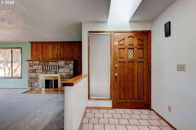 entryway with a textured ceiling, a fireplace, and light colored carpet