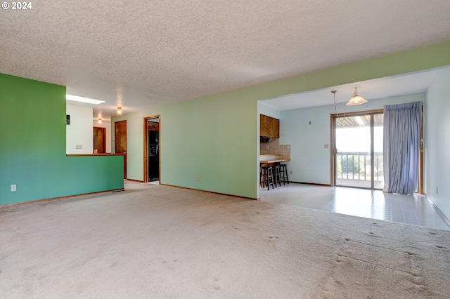 unfurnished living room with light carpet and a textured ceiling