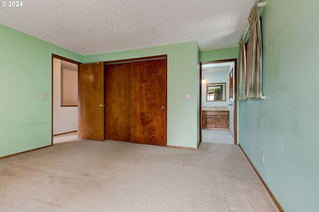 unfurnished bedroom featuring sink, a textured ceiling, light colored carpet, and a closet