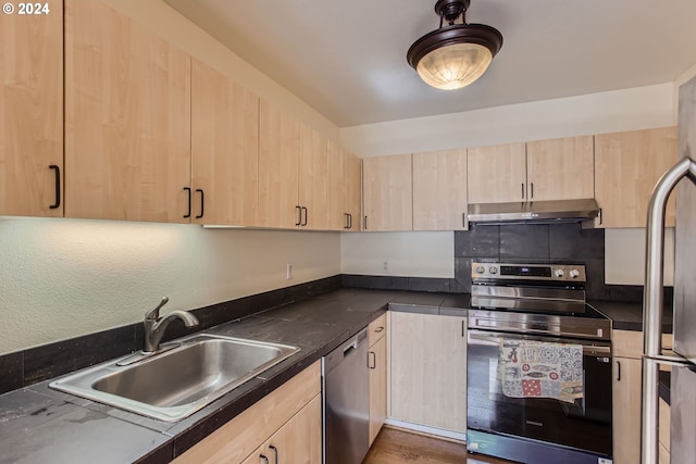 kitchen with light brown cabinetry, stainless steel appliances, and sink