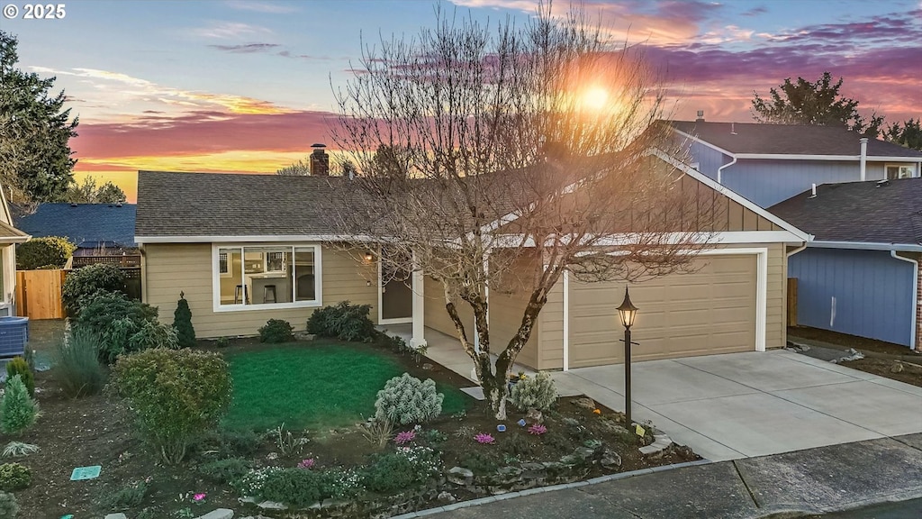 view of front of house with cooling unit, a garage, and a lawn