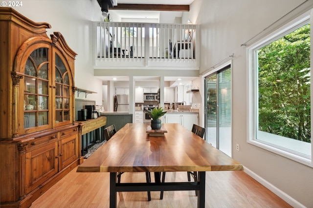 dining room featuring a towering ceiling, a wealth of natural light, and light wood-type flooring