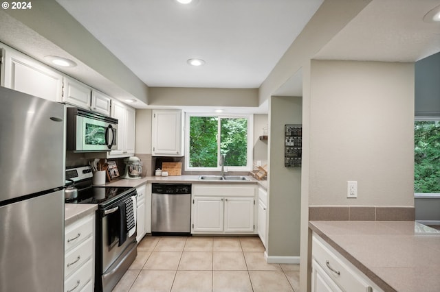 kitchen with light tile patterned flooring, appliances with stainless steel finishes, sink, and white cabinets