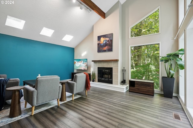 living room with dark wood-type flooring, rail lighting, high vaulted ceiling, a textured ceiling, and a tile fireplace