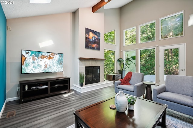 living room with a tiled fireplace, hardwood / wood-style floors, high vaulted ceiling, and beam ceiling