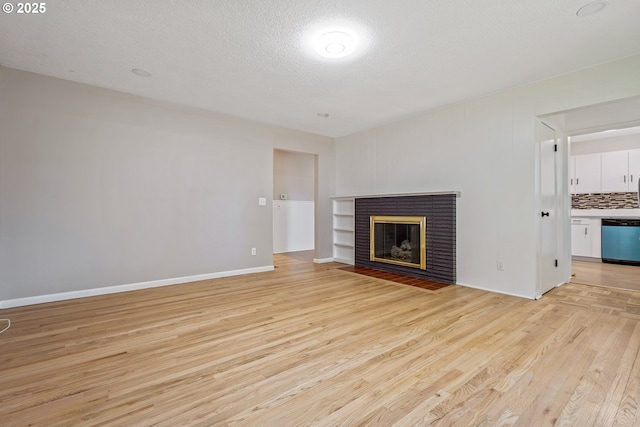 unfurnished living room featuring light hardwood / wood-style flooring, a fireplace, and a textured ceiling