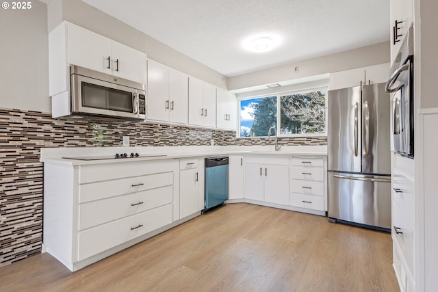 kitchen with sink, white cabinetry, light hardwood / wood-style flooring, stainless steel appliances, and backsplash