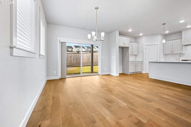 unfurnished living room featuring light hardwood / wood-style flooring and a notable chandelier