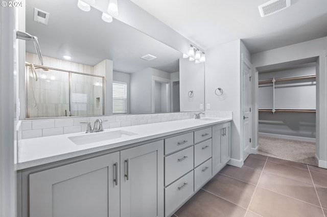 bathroom featuring tasteful backsplash, vanity, a shower with door, and tile patterned flooring