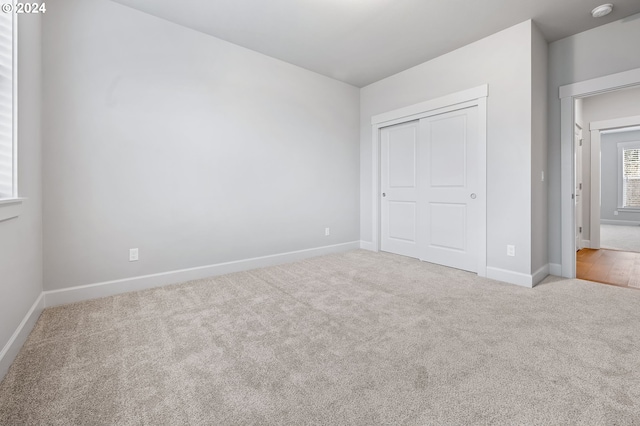 unfurnished bedroom featuring light colored carpet and a closet