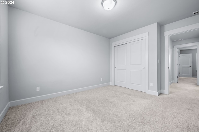 unfurnished bedroom with light colored carpet and a closet