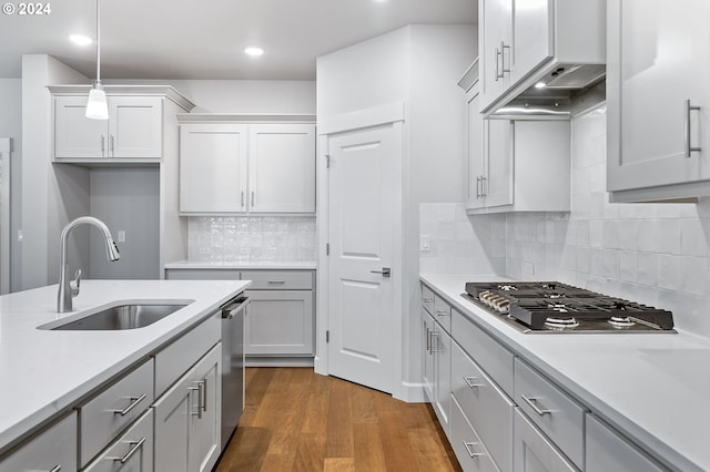 kitchen featuring sink, appliances with stainless steel finishes, backsplash, dark hardwood / wood-style floors, and decorative light fixtures