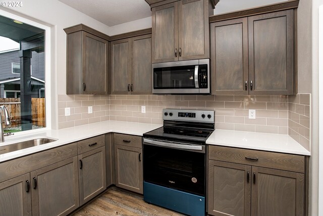 kitchen with decorative backsplash, light hardwood / wood-style floors, sink, and stainless steel appliances