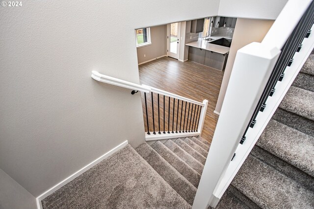 stairs with hardwood / wood-style floors and sink