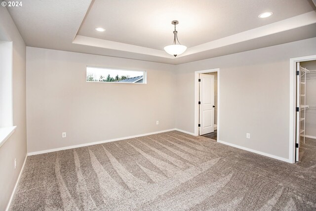 unfurnished room featuring a raised ceiling and dark carpet