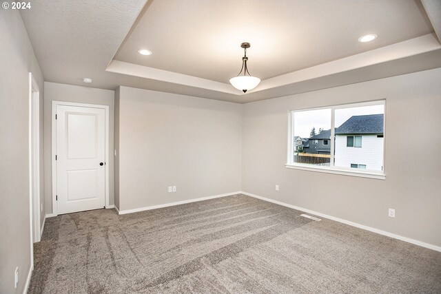 carpeted empty room featuring a tray ceiling