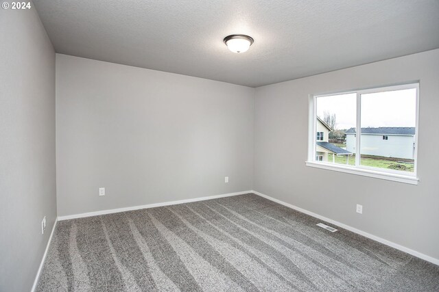 carpeted empty room with a water view and a textured ceiling