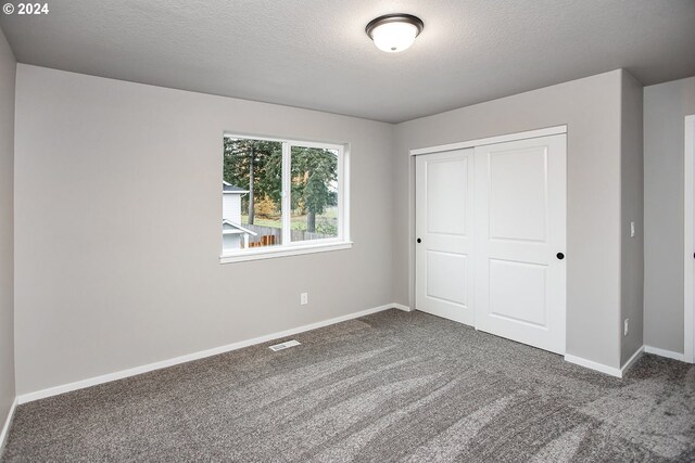 unfurnished bedroom with carpet flooring, a textured ceiling, and a closet