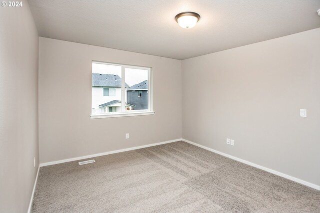 carpeted empty room with a textured ceiling