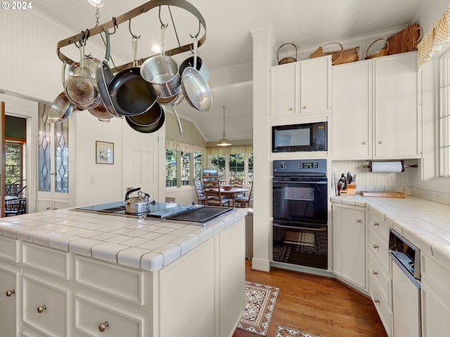 kitchen featuring black appliances, a kitchen island, white cabinetry, and tile counters