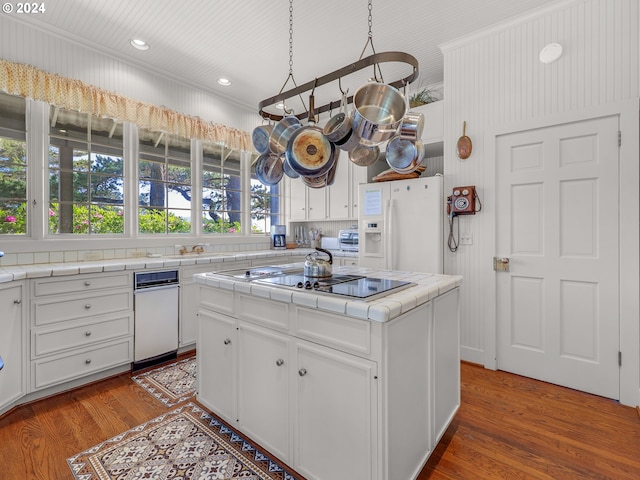 kitchen with crown molding, white refrigerator with ice dispenser, white cabinets, a kitchen island, and tile countertops