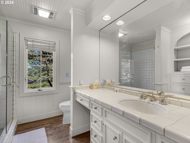 bathroom featuring toilet, hardwood / wood-style flooring, walk in shower, ornamental molding, and vanity