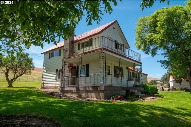 rear view of house featuring a yard, a porch, and a balcony