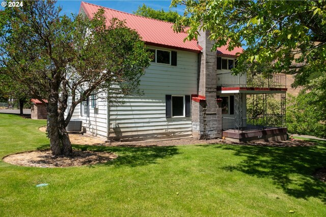 back of house featuring a balcony and a yard