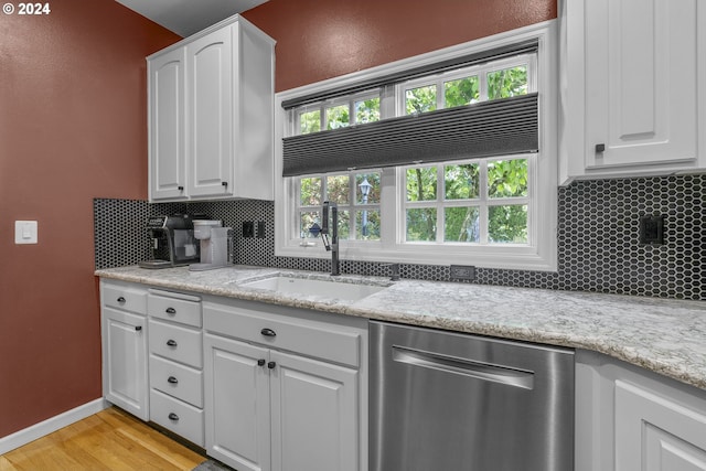 kitchen featuring white cabinetry, sink, light hardwood / wood-style flooring, stainless steel dishwasher, and backsplash