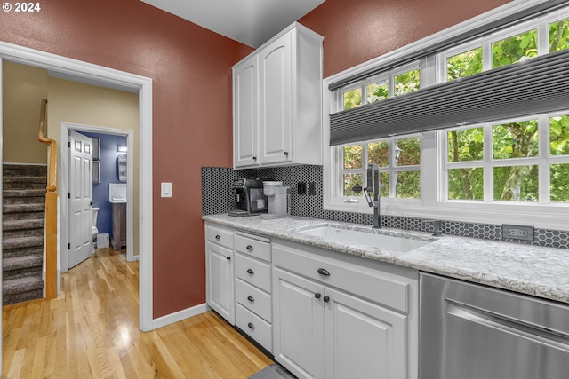 kitchen featuring stainless steel dishwasher, white cabinetry, sink, and light hardwood / wood-style flooring