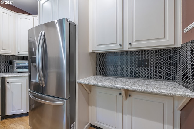 kitchen featuring white cabinets, tasteful backsplash, stainless steel refrigerator with ice dispenser, and light hardwood / wood-style flooring