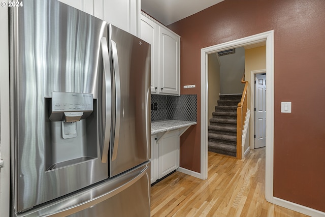 kitchen featuring white cabinets, light stone counters, stainless steel fridge with ice dispenser, and light hardwood / wood-style flooring