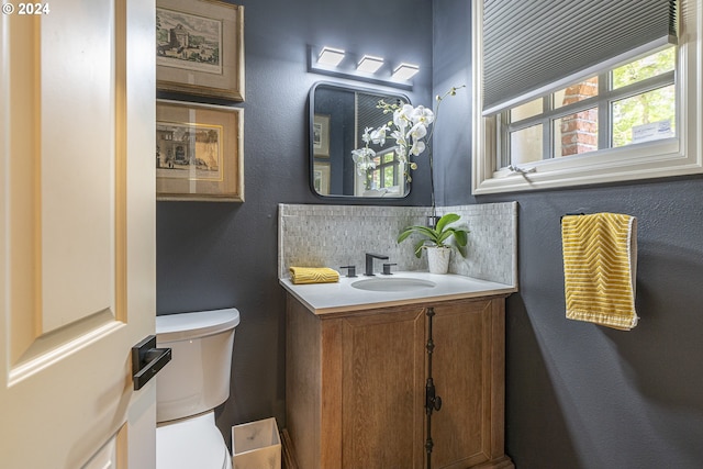 bathroom with decorative backsplash, toilet, and vanity