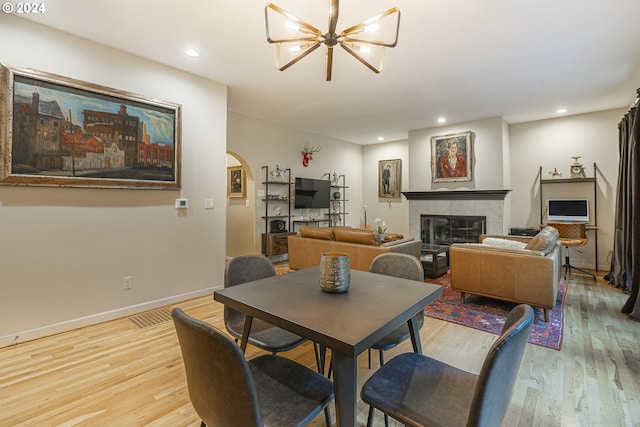 dining room featuring a notable chandelier, a tile fireplace, and light hardwood / wood-style flooring