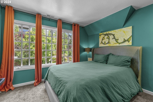 bedroom with a textured ceiling, carpet floors, and lofted ceiling